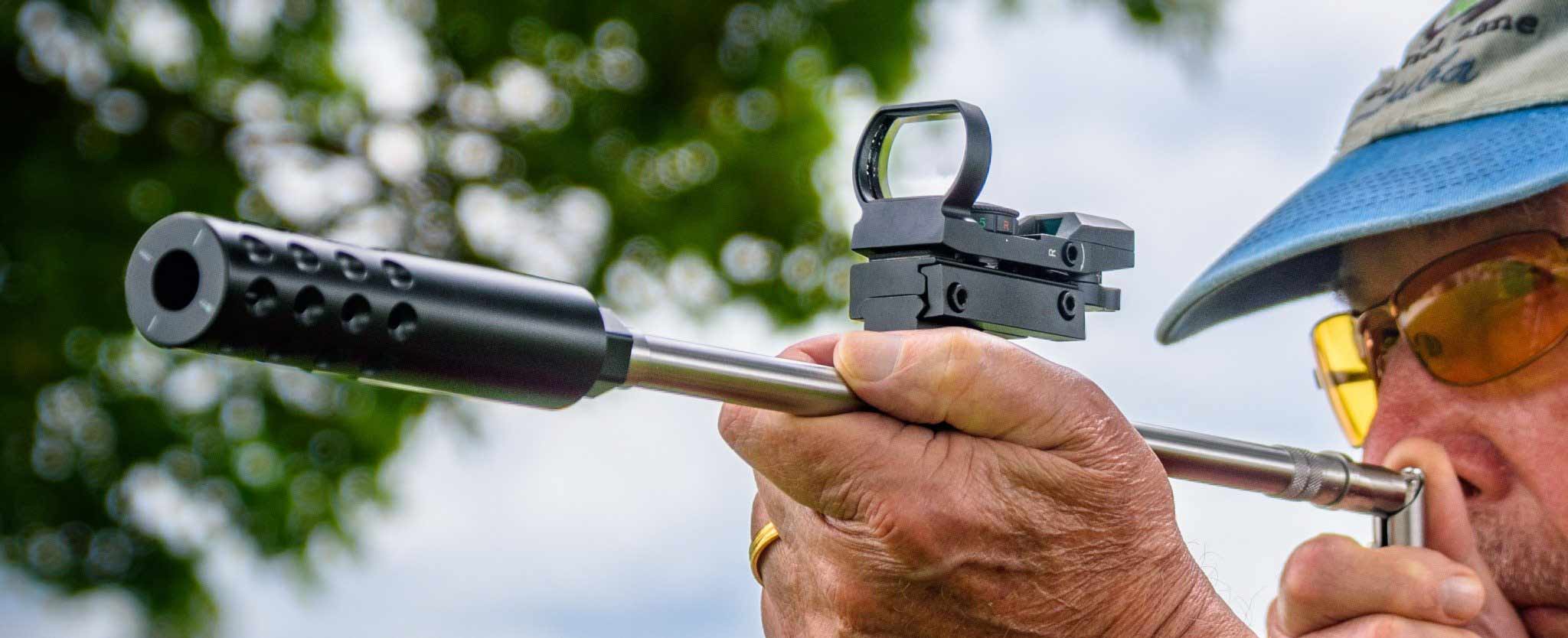Robert J. Braverman, in sunglasses and a cap, holding the re-engineered Stinger in a two-handed grip outdoors